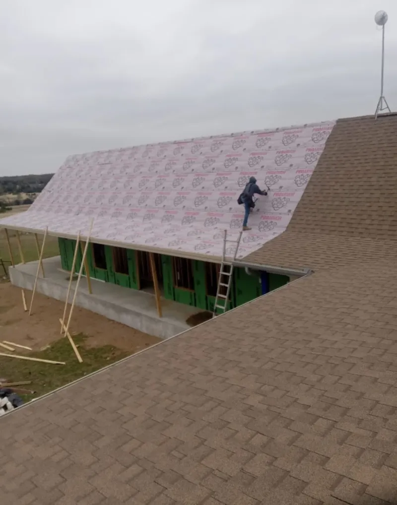 Worker preparing underlayment for a metal roof installation in Williamson